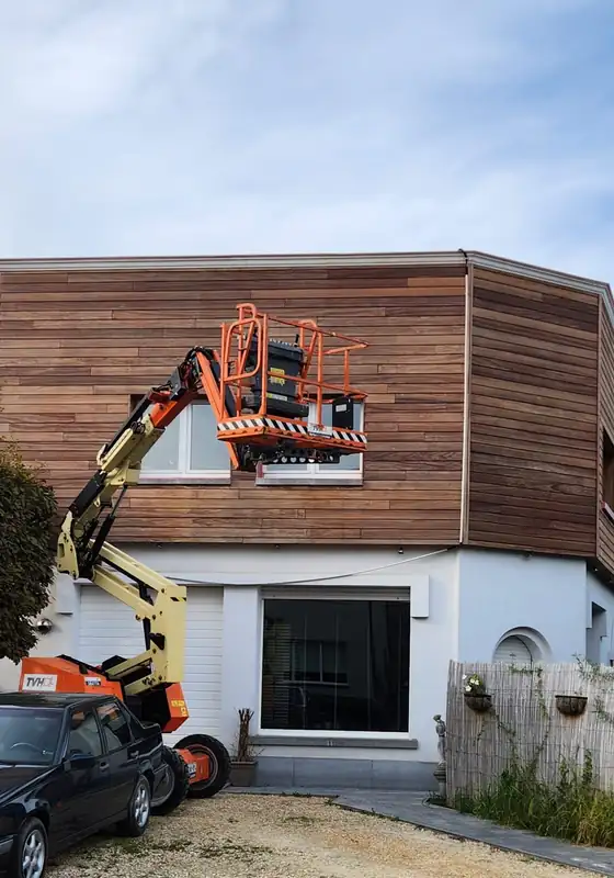 Hoogtewerker aan een houten gevelbekleding