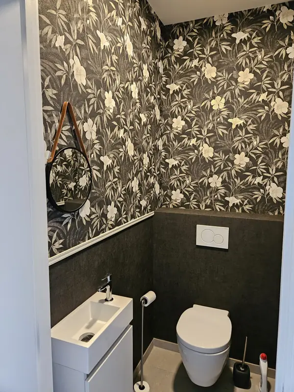 Toilet met donker bloemenbehang en witte lambrisering