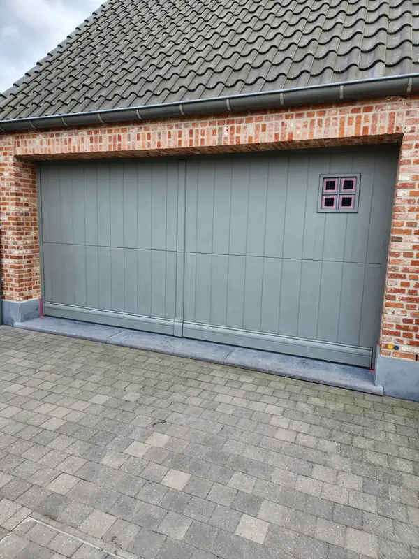 Grijze garagepoort in een bakstenen gevel