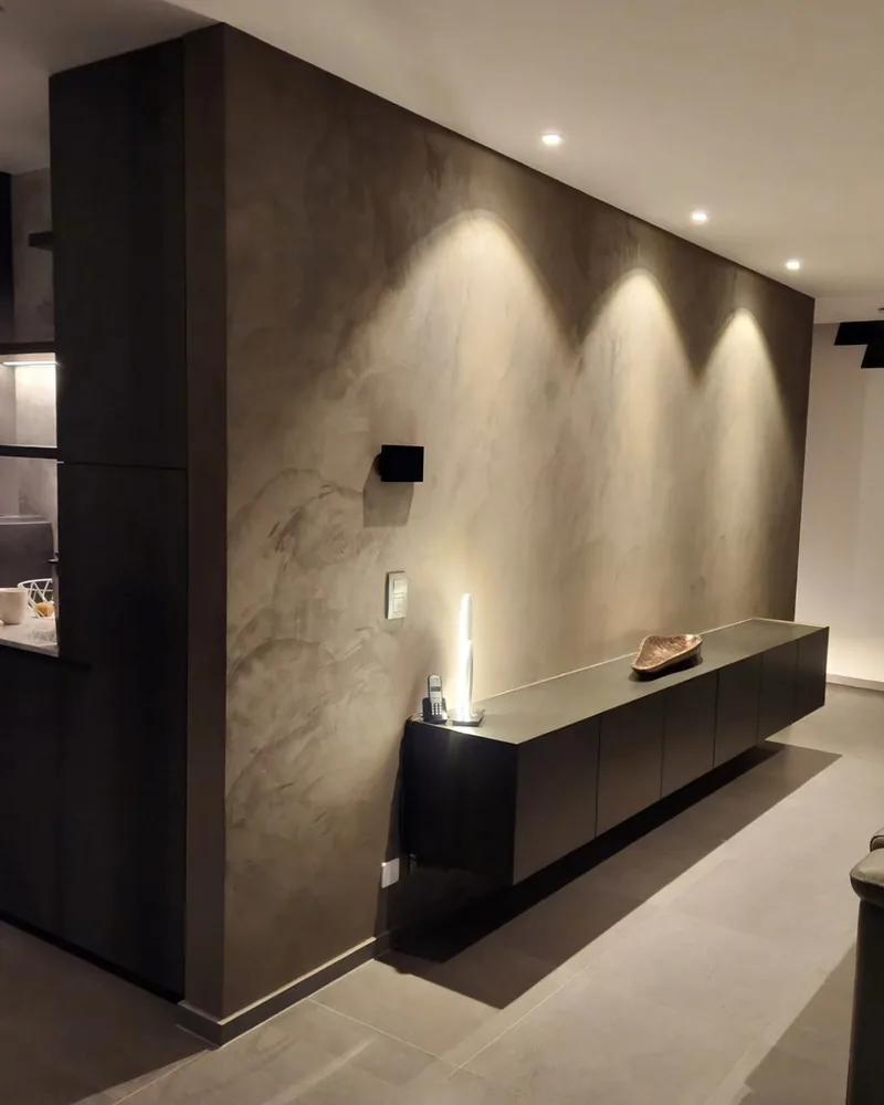 Leefruimte met een donkere, decoratief afgewerkte wand en spotverlichting