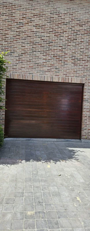 Bruine garagepoort in een bakstenen gevel